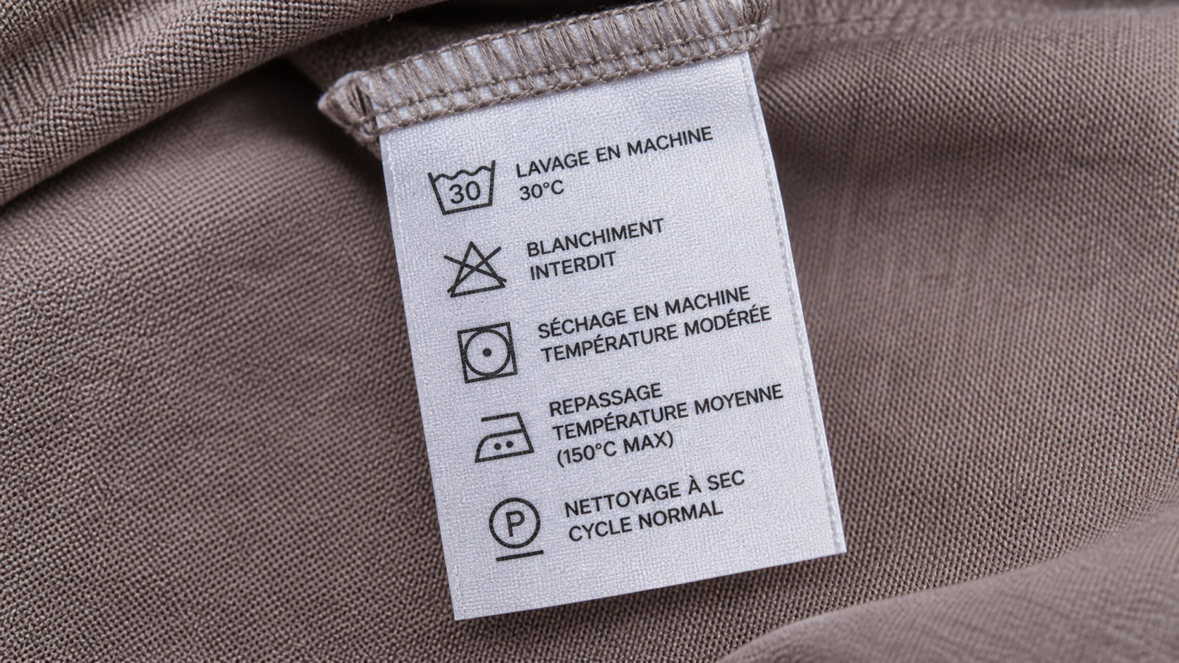 Étiquette textile montrant les pictogrammes de lavage, séchage et repassage